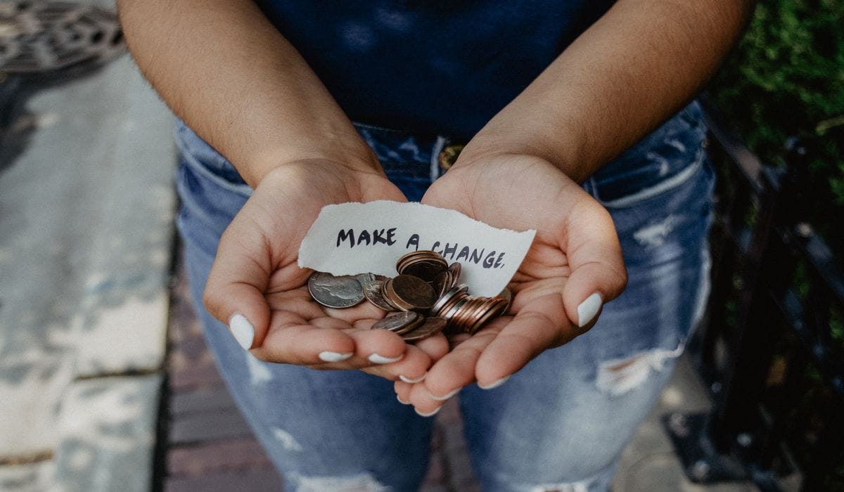Person Holding Coins With Make A Change Sign