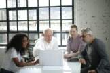 team gathered around laptop