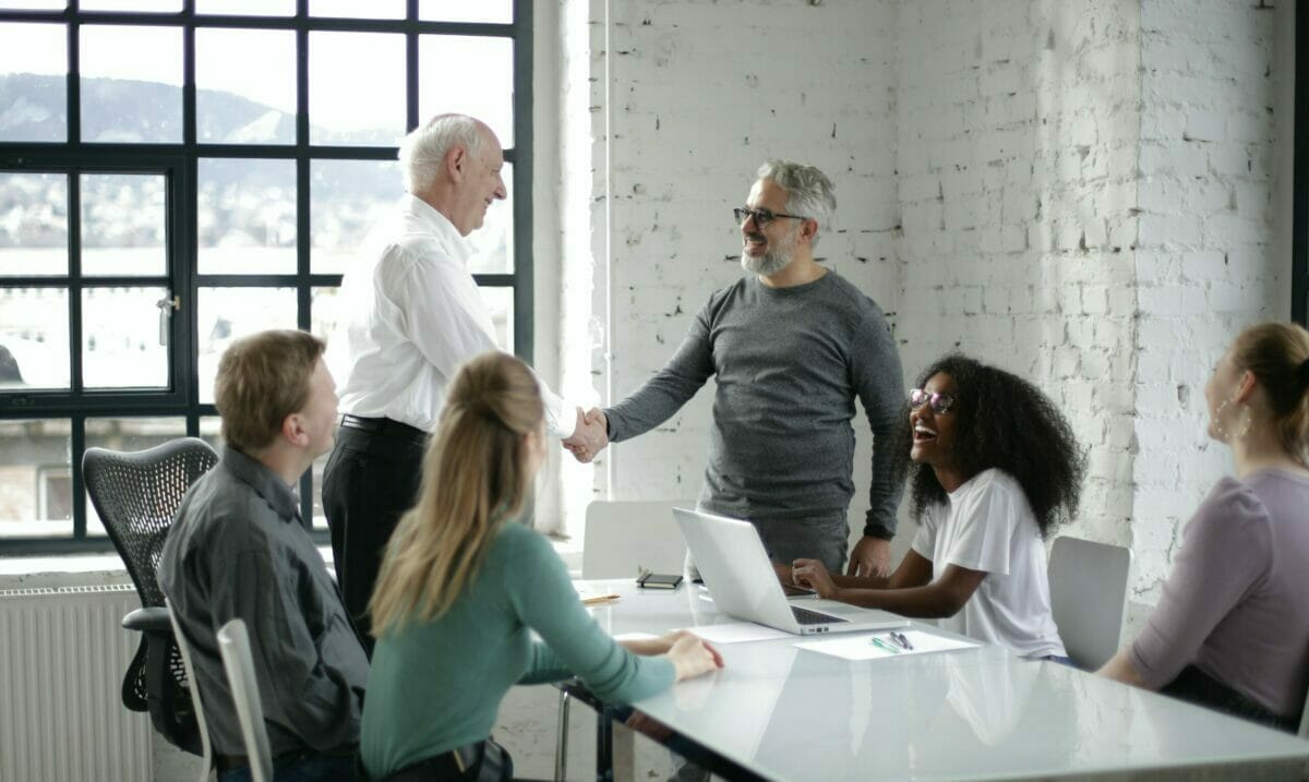 Cheerful Colleagues Shaking Hands During Meeting In Modern Workspace