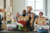 A Group Of Volunteers Sorting Clothes Into Containers Posing Together
